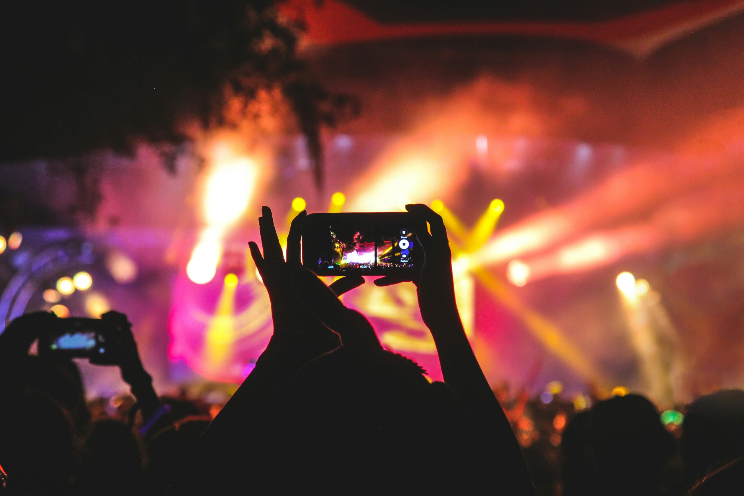 Concert goer capturing a video of an artist performing at a concert.